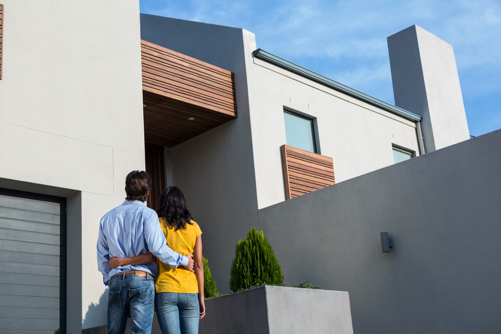 couple looking at their new home they just purchases on a sunny day